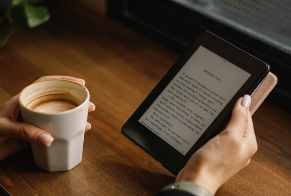 a person sitting at a table with a tablet and a cup of coffee