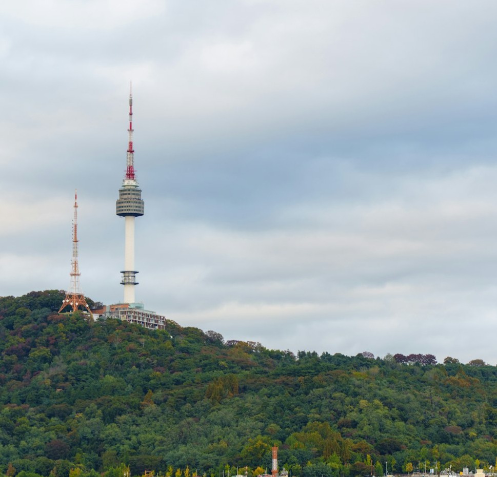 The n seoul tower is seen atop a green hill