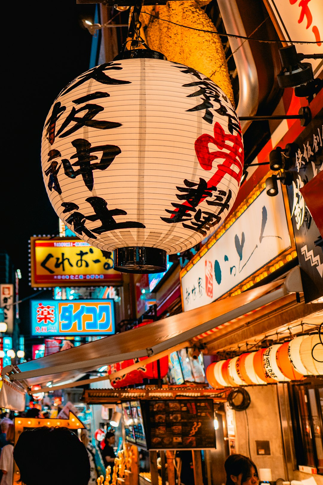 Large japanese lantern illuminates a vibrant street market at night