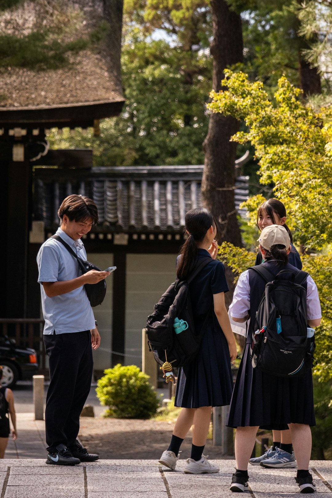 Young students gathered outdoors, one checking a phone