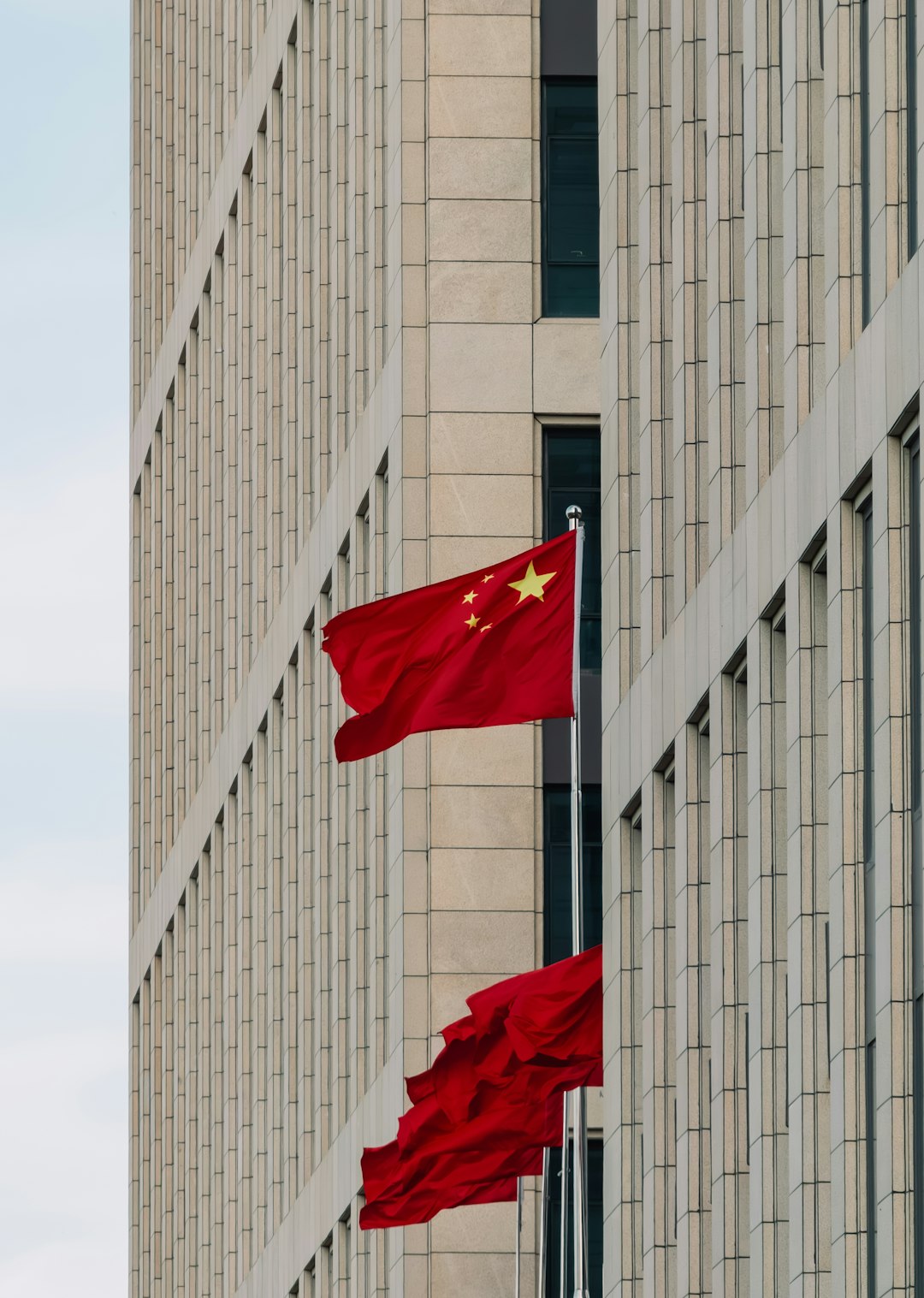 Chinese flags waving in front of a modern building