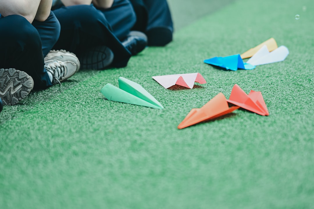 Colorful paper airplanes scattered on green artificial grass