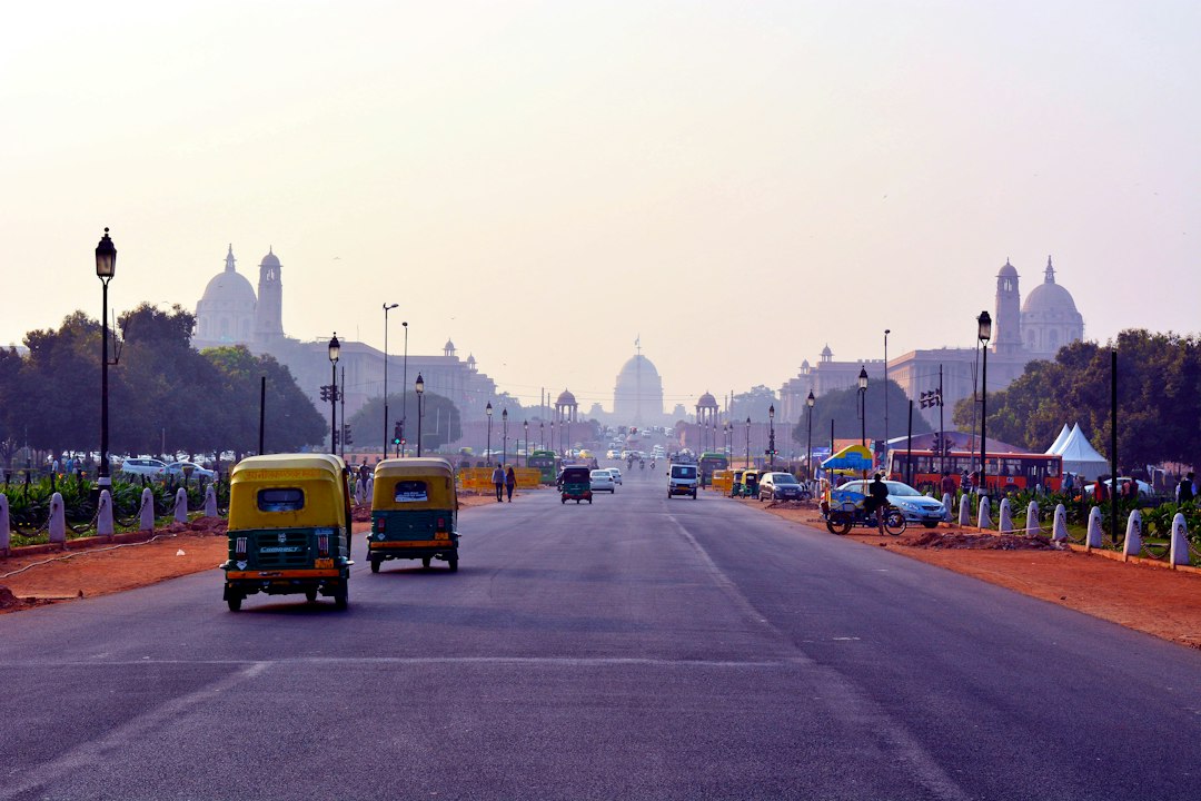 Auto rickshaws driving on a wide road toward the Rashtrapati Bhavan in New Delhi